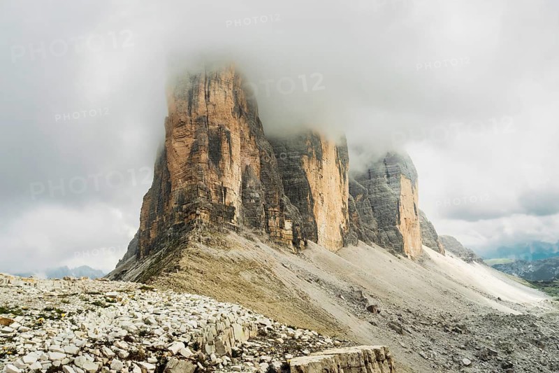 Dramatic misty Tre Cime di Lavaredo area. Dynamic clouds after rain move over the rugged limestone peaks of the Italian Dolomites. Three sisters circular loop popular trail summer