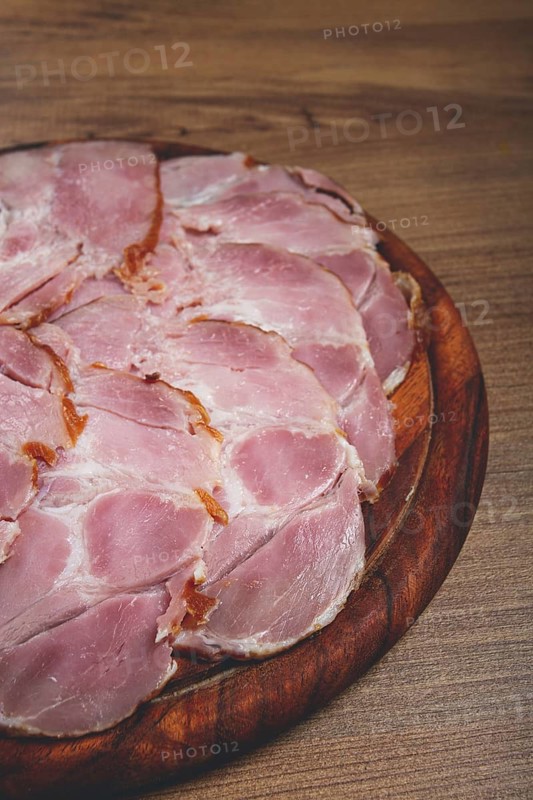Sliced pork neck, boiled and smoked, smoked pork neck, sliced, on a wooden chopping board, close-up