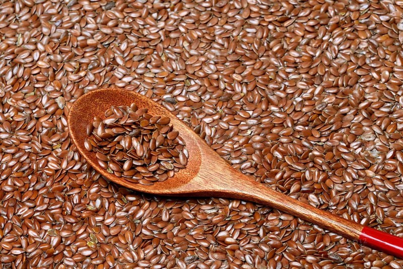 Linseed with wooden spoon, seeds of the common flax (Linum usitatissimum)