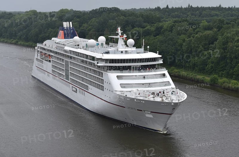A large cruise ship sails on a wooded river under cloudy skies, cruise ship EUROPA 2 sails through the Kiel Canal, NOK, Kiel Canal, Schleswig-Holstein, Germany