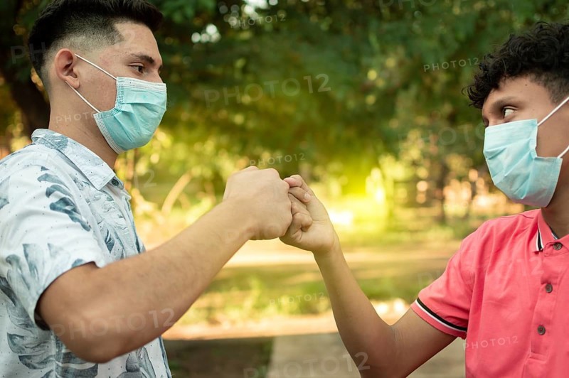 Two young men clashing their fists, image of two young men bumping their fists in a friendly way, close up of two fists bumping in a friendly way