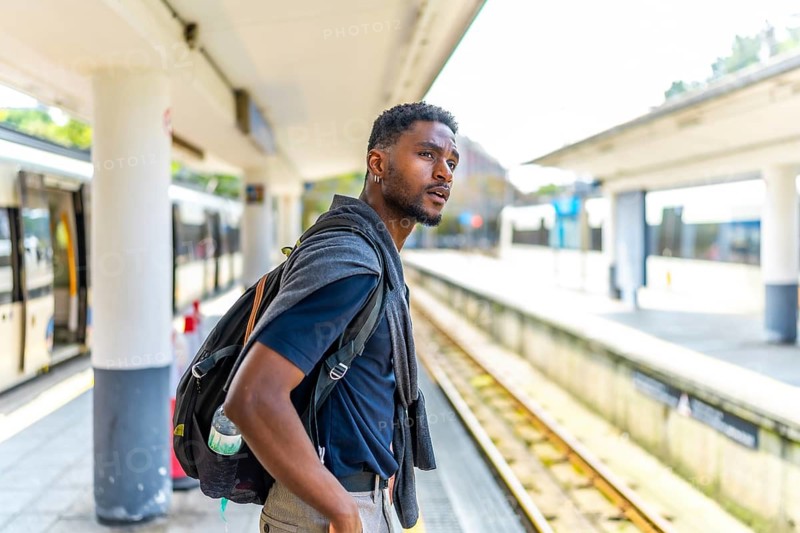 Side view and copy space of an African young businessman waiting for the train in the platform