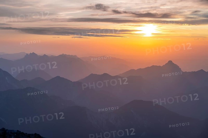 Silhouettes of mountains at sunset with sun, view from the summit of the Zugspitze, Wetterstein range, Northern Limestone Alps, Bavaria, Germany
