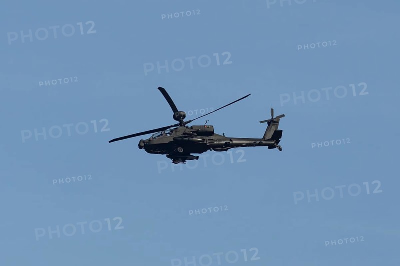 Apache AH-64E military helicopter aircraft of the Royal Army air corp flying in a blue sky, England, United Kingdom