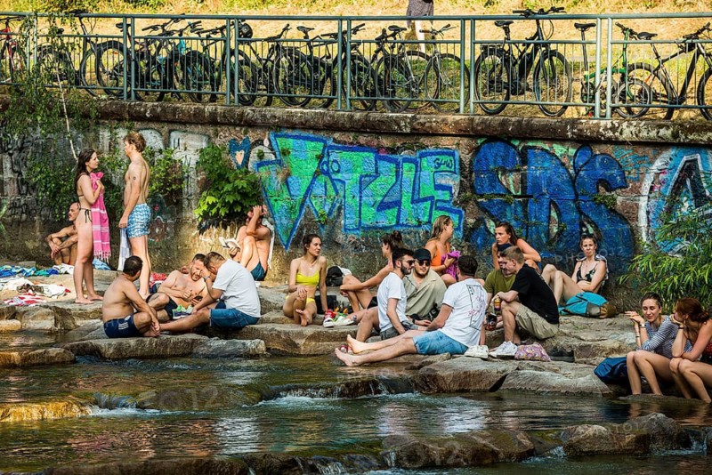 Young people sitting by and in the river, bathing in the city, heat, heat wave, climate change, Dreisam, Freiburg im Breisgau, Black Forest, Baden-Württemberg, southern Germany, Germany