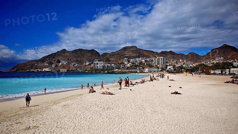Sunny sandy beach 'Praia da Laginha' with holidaymakers and blue sea against a mountain backdrop, Mindelo, Sao Vicente, Cabo Verde, Cape Verde, Cape Verde