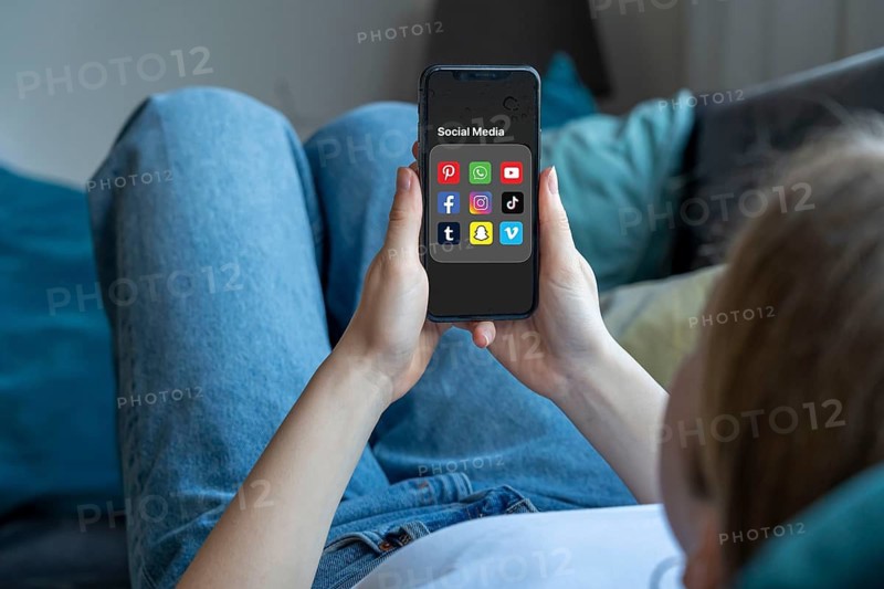 Symbolic image of social media use by young people, children, young woman, girl, 14 years old, folder with various social media platforms on the mobile phone