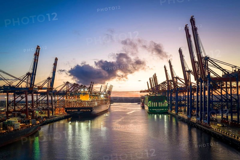 Aerial view at Waltershof harbour during the Blue Hour with Eurogate Container Terminal Hamburg (CTH) and Container Terminal Burchardkai (CTB) with the brightly lit Ever Meed, Manila Express and Fort Desaix in the background, Hamburg, Germany