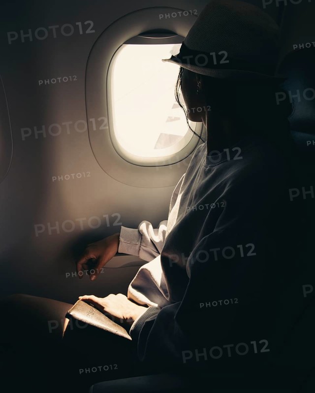 Close up silhouette of caucasian woman looks out the window of an flying airplane. Passenger on the plane resting beside the window