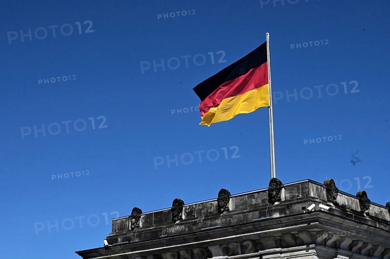 One of the towers of the Reichstag and a waving German flag against a blue sky