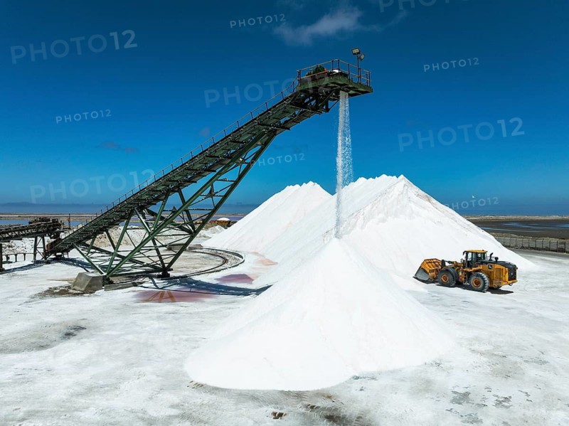 Salt heaps with conveyor belt and excavator at the Walvis Bay Salt works. Aerial view. Drone shot. Walvis Bay, Namibia