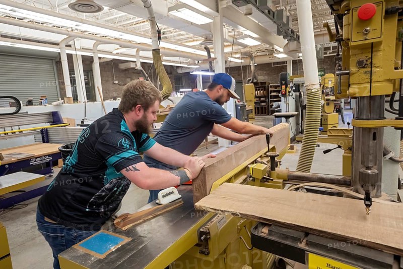 Hindman, Kentucky - Workers make high-quality guitars, dulcimers, mandolins, and ukeleles at the nonprofit Troublesome Creek Stringed Instrument Company. Most workers are recovering from an addiction. Anthony Parsons (left) and shop foreman Kris Patrick smooth a large piece of black walnut that will be used for dulcimers
