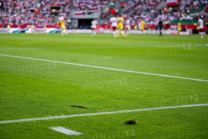 Close up on a damaged green grass turf with a divot on the white line during a soccer match in Wroclaw, Poland