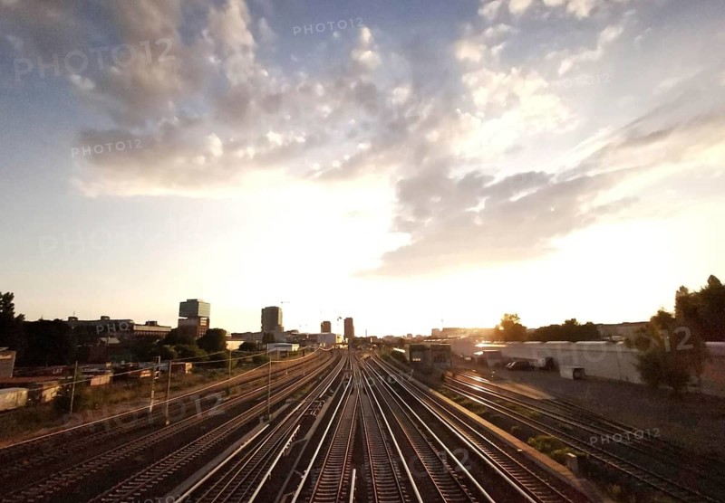 Railway tracks at sunset surrounded by buildings and a cloudy sky, Berlin