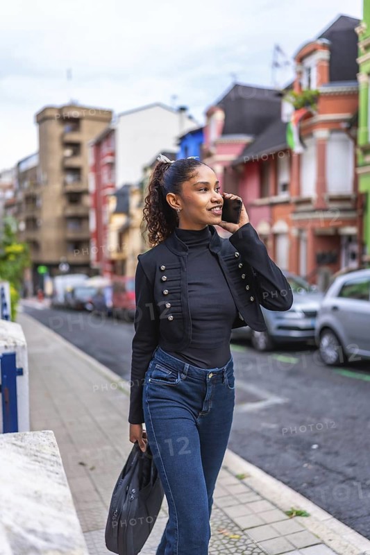 Vertical photo of a beauty african american businesswoman talking to the cellphone walking down street