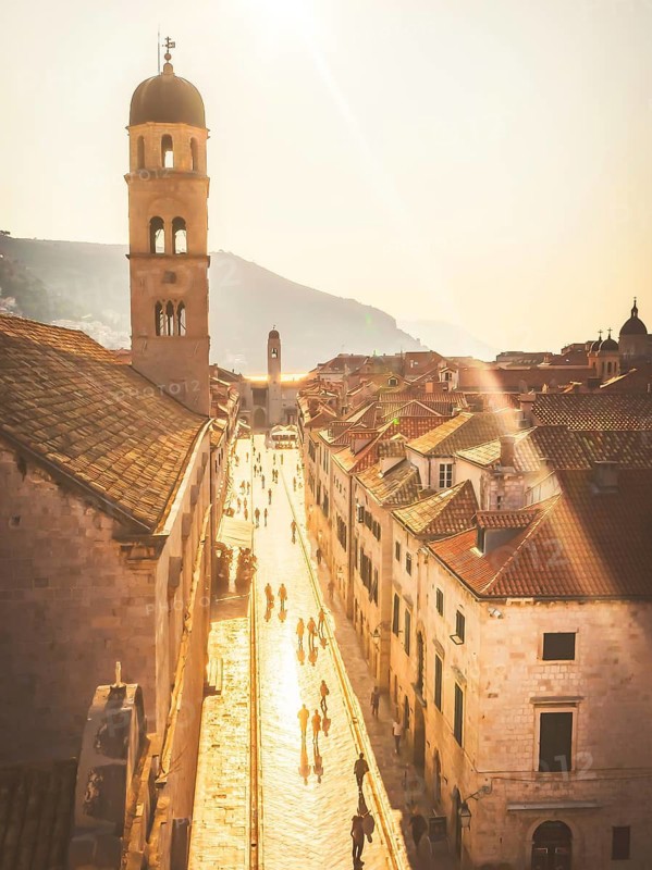 Golden hour view of Dubrovnik Old Town, Croatia. Scenic panorama of Stradun street with Franciscan Monastery Bell Tower, historic architecture and UNESCO World Heritage site