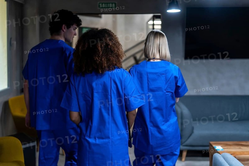Healthcare professionals wearing blue scrubs walking together down a hospital corridor, symbolizing unity, collaboration, and dedication in the medical field