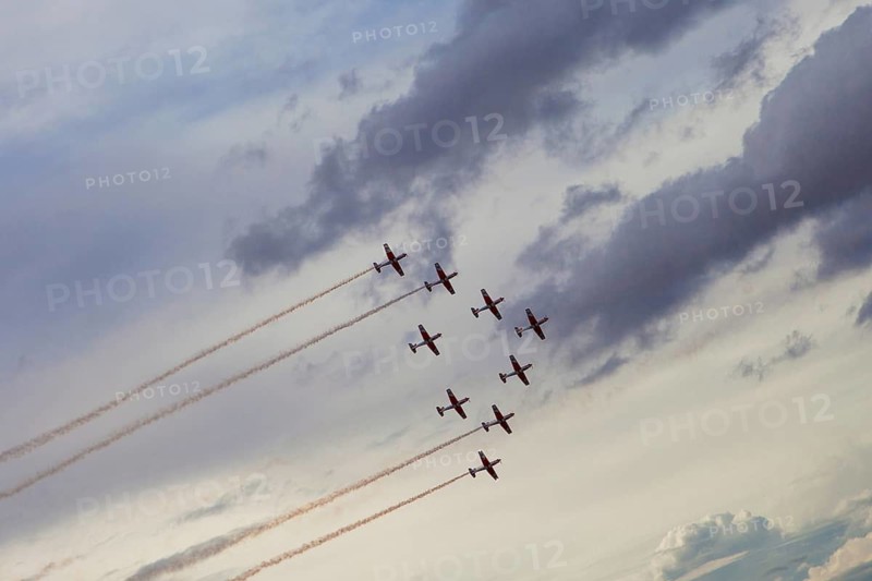Daring aerobatic team showcases stunning formations against a dramatic cloudy sky during an air show at Torrejon Air Base, Spain, captivating the audience below