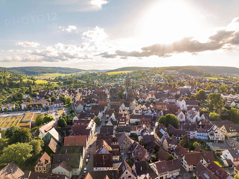 Malebic urban aerial view at sunset with numerous roofs, a church and surrounding hills, Weil der Stadt, Germany