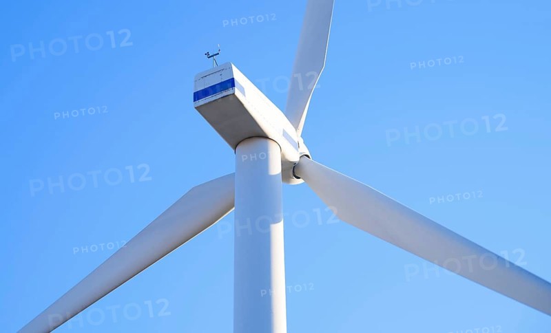 Close-up of a wind turbine set against a clear blue sky in California, USA. The image captures the sleek, white blades and structural details, symbolizing renewable energy and innovation