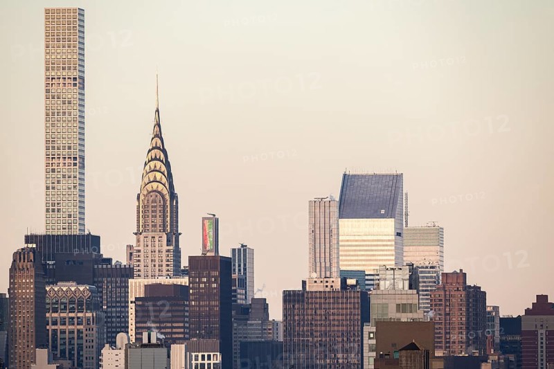 A close view of New York City's skyline showcasing iconic skyscrapers such as the Chrysler Building, set against a dusky sky. The image captures the architectural diversity and urban aesthetics of New York
