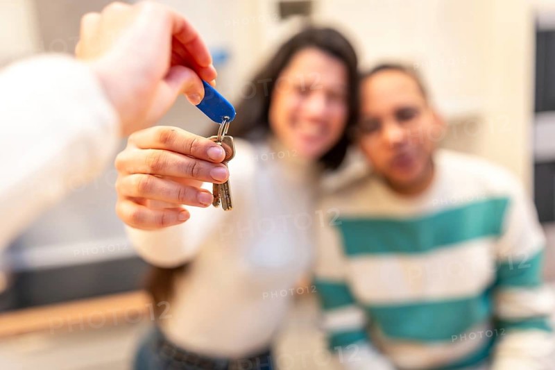 Real estate agent handing house keys to a smiling couple celebrating new home ownership and moving into their dream property, happy moment and successful transaction