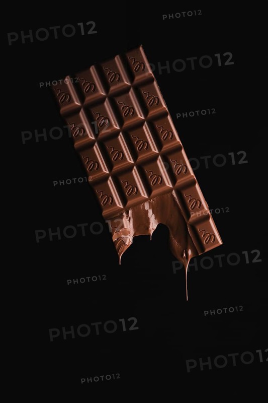 A floating, partially melted chocolate bar on a black background