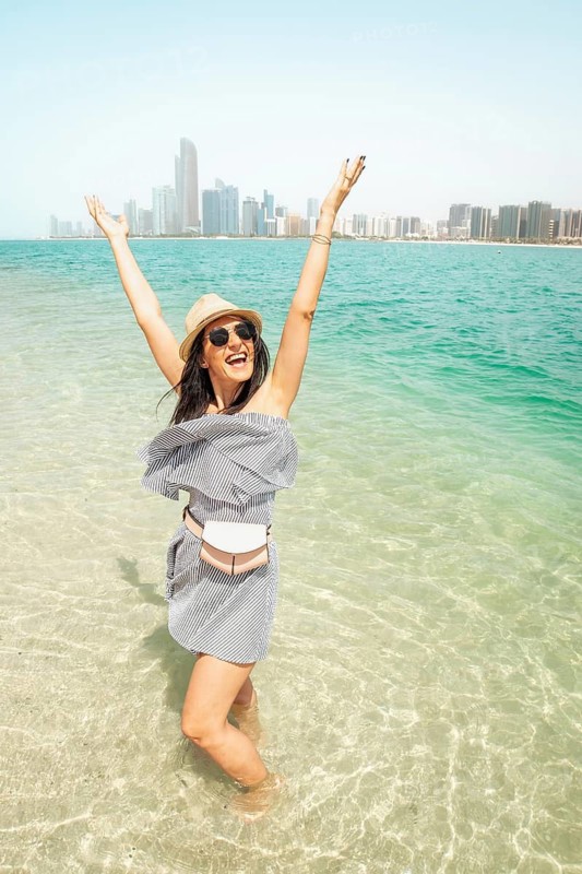 Young woman on refreshing turquoise water enjoy beach have fun visiting UAE capital Abu Dhabi relax enjoy coastline view - Happy tourist walking sightseeing UAE - Travel and vacation lifestyle concept