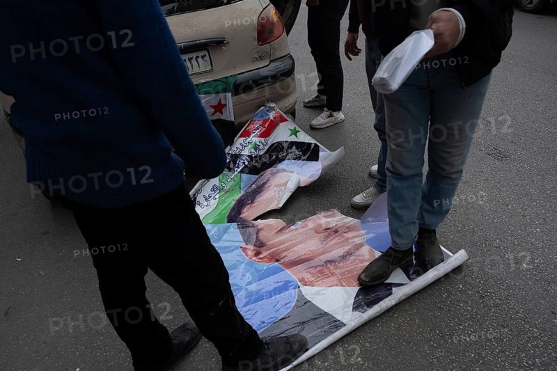 Damascus, Syria. December 8th 2025. Syrians stamp on a poster of the former Syrian president Bashar al Assad during celebrations after one year of the fall of the Assad regime, Damascus, Syria