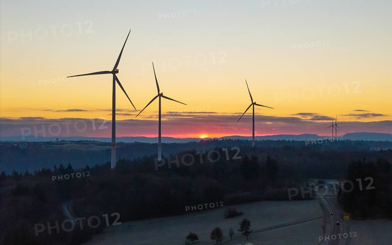 Wind turbines with a sunrise over a mountain landscape in the background, Rems Valley, Baden-Württemberg, Germany