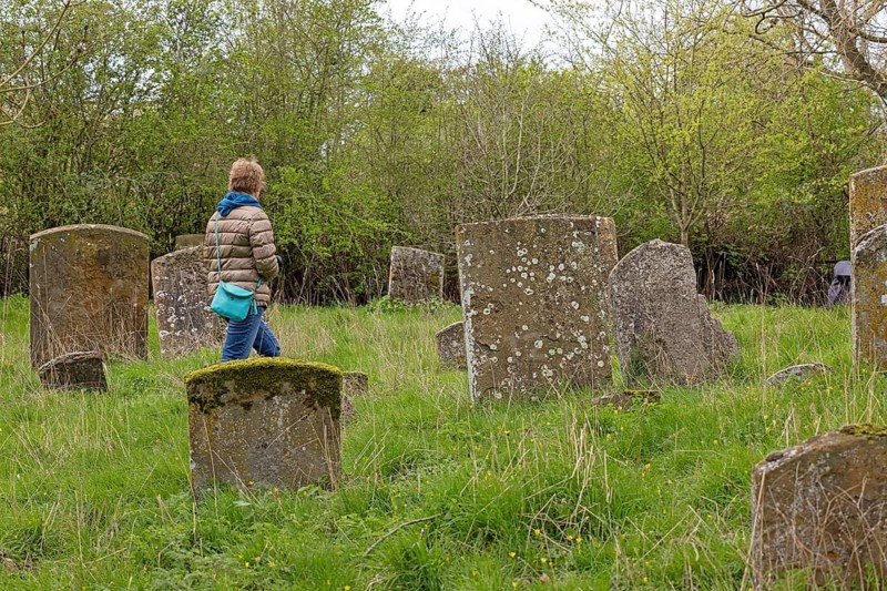 Woman walking through cemetery of The Old Church of St James, headstones, Alveston, Stratford-upon-Avon, Warwickshire, England, Great Britain