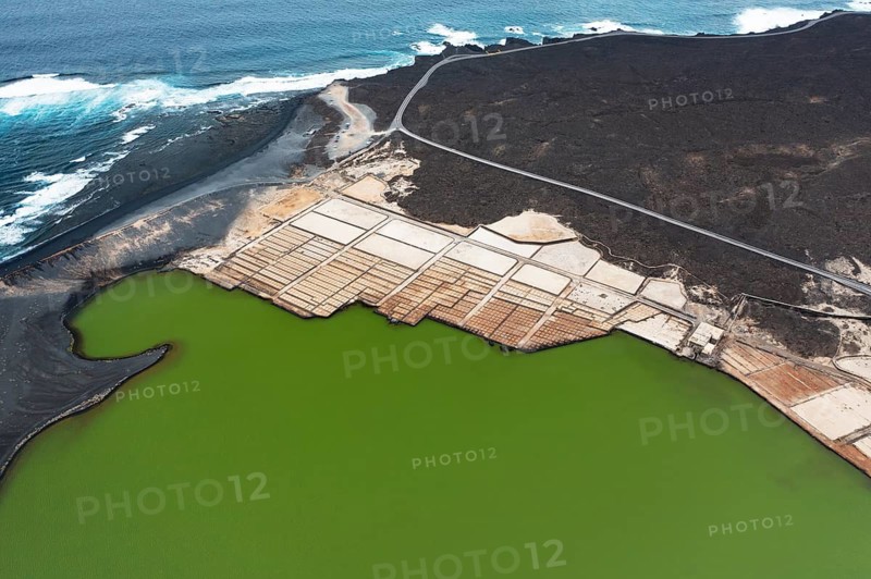 Aerial view of the vibrant green saltwater lagoon and geometric salt pans at Los Salares de Janubio, Lanzarote, contrasting with black volcanic landscape