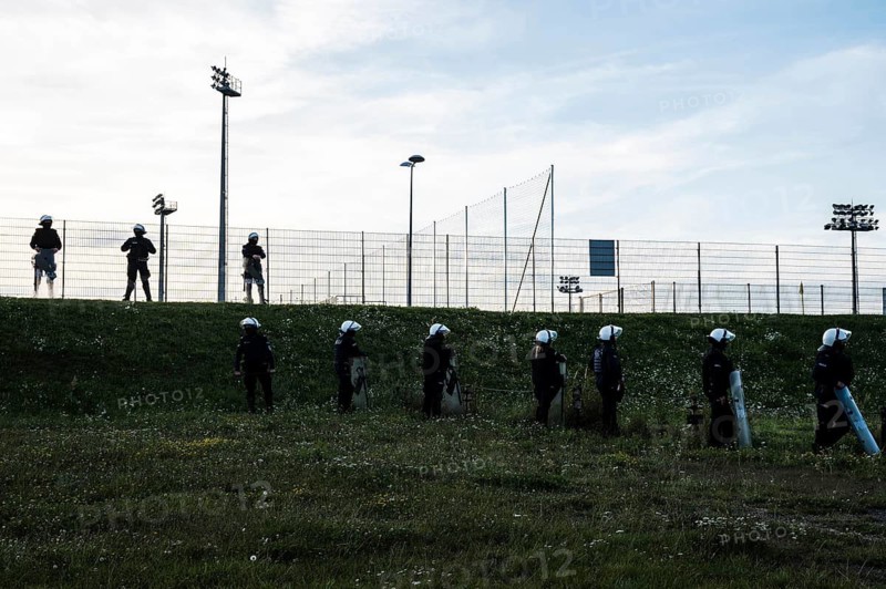 Silhouettes of policemen standing next to the football field (inscription in Polish Police) in Lubin, Poland