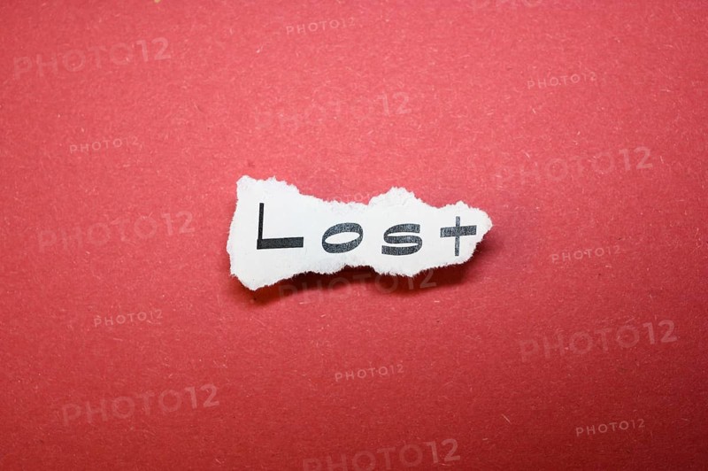 The word 'Lost' on torn paper on a red background symbolises forlornness