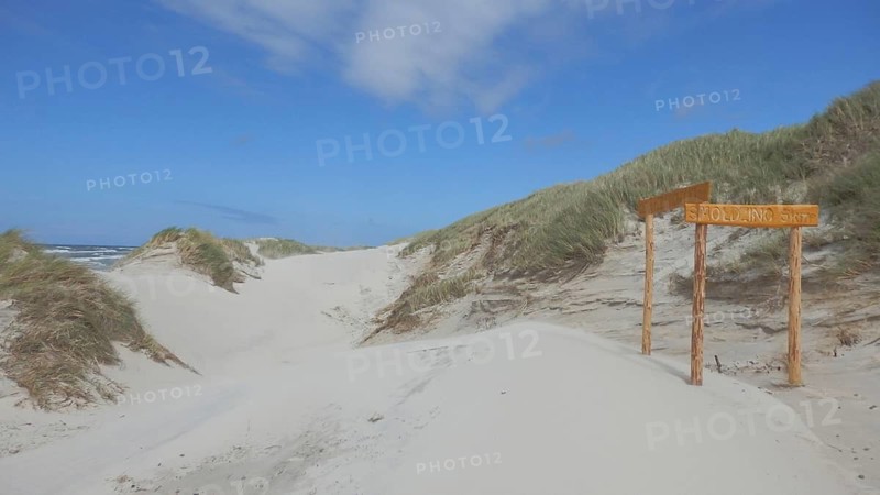 Sand dunes on a wide beach with a wooden sign and blue sky, long-distance cycle path, dune landscape near Leba, R10, Baltic Sea, Poland