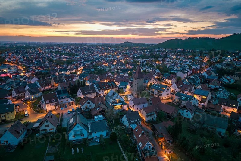 City view at dusk with illuminated houses and a church under a picturesque evening sky, Korb im Rems Valley, Baden-Württemberg, Germany
