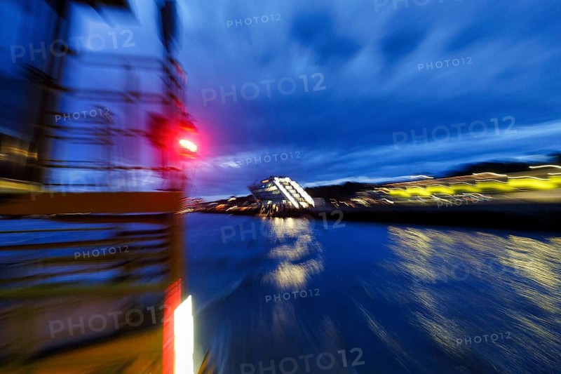 Red light signal on harbor ferry, view of illuminated Dockland office building, harbor tour at dusk, dynamic, abstract mopping effect, river, Elbe, Hamburg, Germany