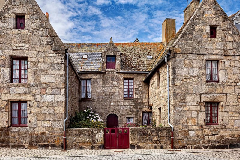 Historic stone house with gabled roofs and old bricks under a blue sky, historic stone house in Brittany