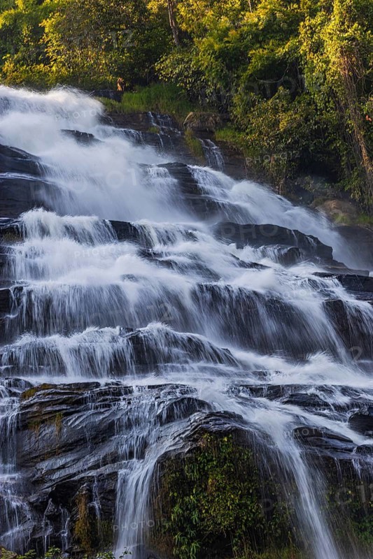 Mae Ya waterfall with cascading flowing water surrounded by lush tropical vegetation, near Doi Inthanon National Park, Chiang Mai Province, Thailand