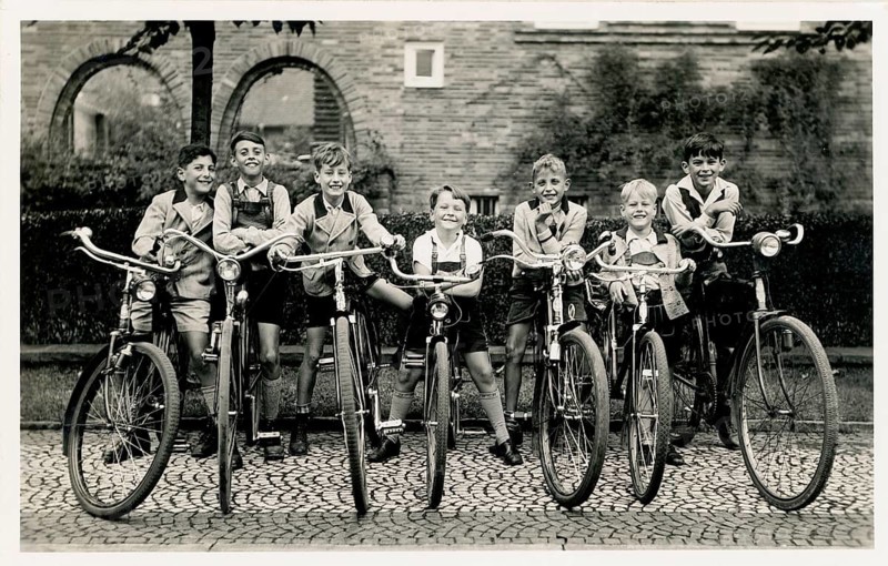 Group of boys, too big bikes, joy, laughter, cheeky, rebellious, twenties, boys standing in a row on a paved road with their bikes