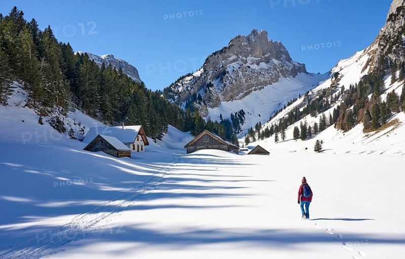 Woman hiking in the snowy mountain landscape of the Alpstein Säntis mountain range, Brülisau, Kanton Appenzell, Switzerland