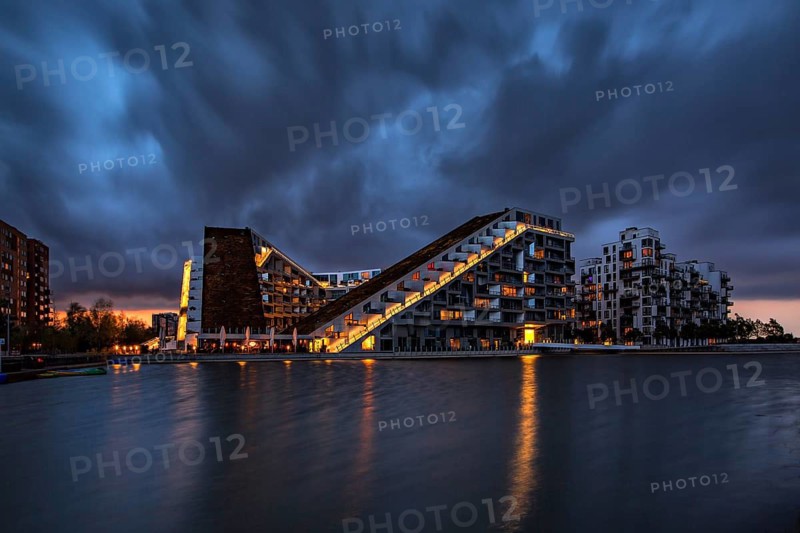 Modernes Gebäude bei Nacht mit dramatischem Himmel und beleuchteten Fenstern am Wasser, Kopenhagen, Dänemark