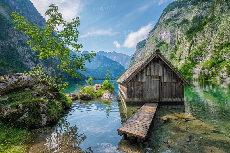 Vibrant summer landscape of the boathouse at Obersee lake with green trees and crystal clear mountain water, Bavaria, Germany