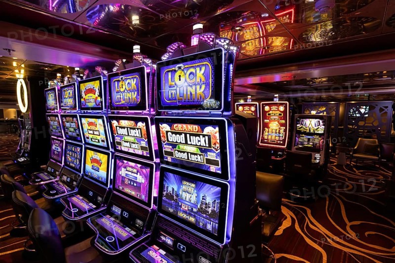 Rows of illuminated slot machines with colorful neon displays on a casino gaming floor, vibrant entertainment and gambling interior at night