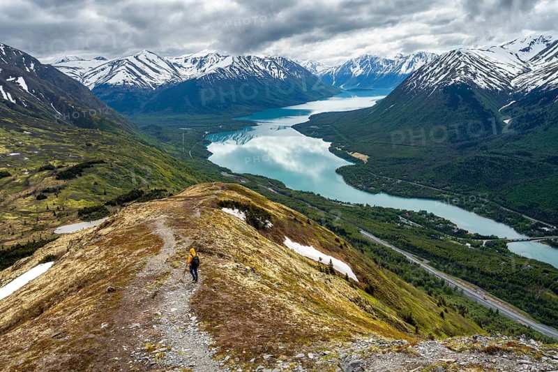 Climbers on a hiking trail on Slaughter Ridge, views of snowy mountains in spring and turquoise Lake Kenai Lake, Cooper Landing, Kenai Peninsula, Alaska, USA