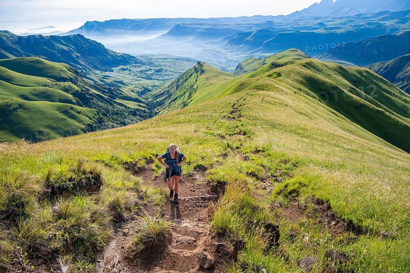 Female hiker on the hiking trail to Cathedral Peak, Green Mountains and Hills, Drakensberg Mountains, KwaZulu-Natal, South Africa
