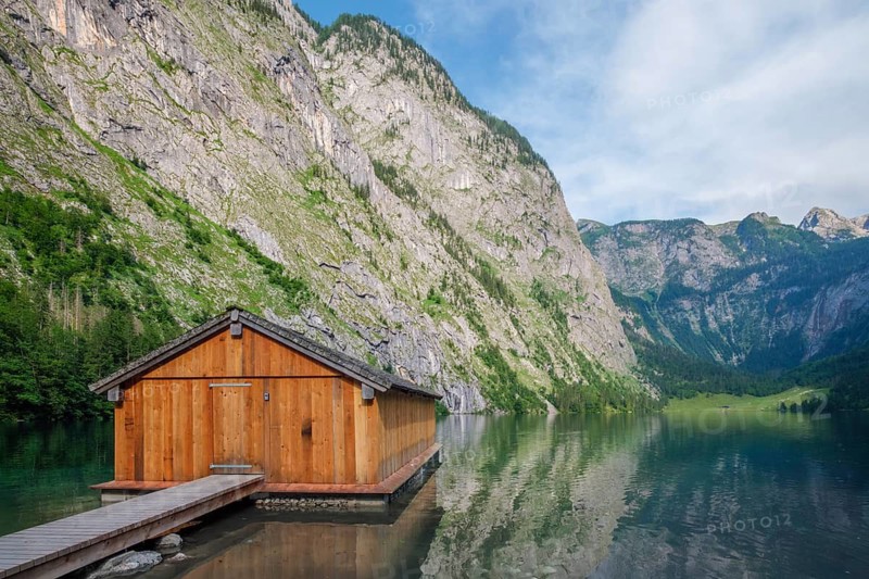 Scenic view of a rustic wooden boathouse and dock on the emerald waters of Obersee lake in Berchtesgaden, Bavaria, Germany