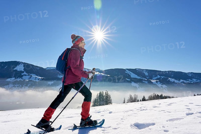 Sportive senior woman hiking with snow shoes in the snowy Allgaeu Alps above Lake Alosee, Immenstadt, Bavria, Germany