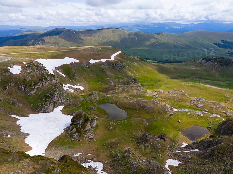 A mountainous landscape with snow and green areas under a cloudy sky, aerial view, Transalpina High Road, Drum na?ional 67C, National Road, Transylvania Alps, Southern Carpathians, Romania