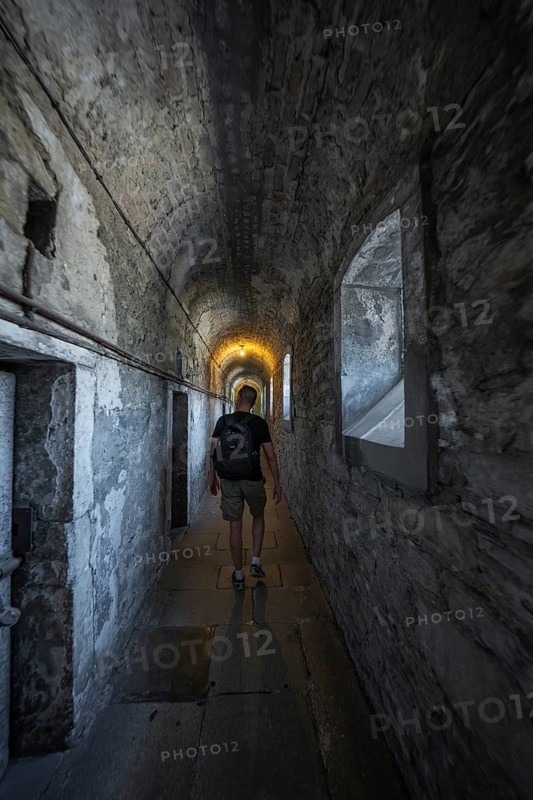 Person with backpack in a gloomy stone corridor, Kilmainham Gaol Prison, Dublin, Ireland